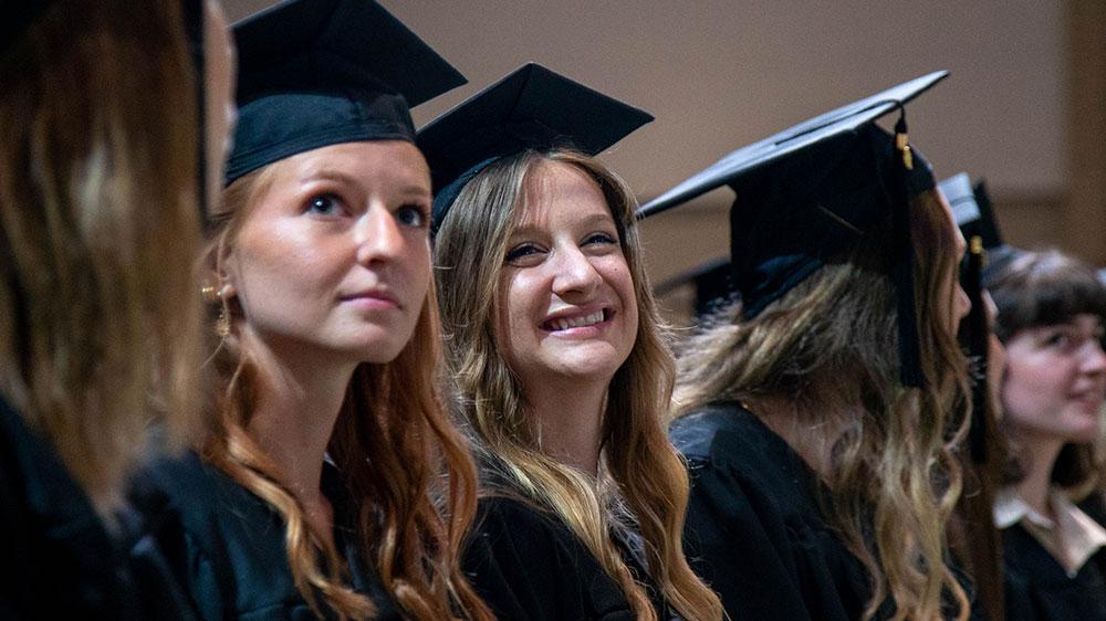 微笑的女孩们戴着毕业帽，穿着毕业礼服